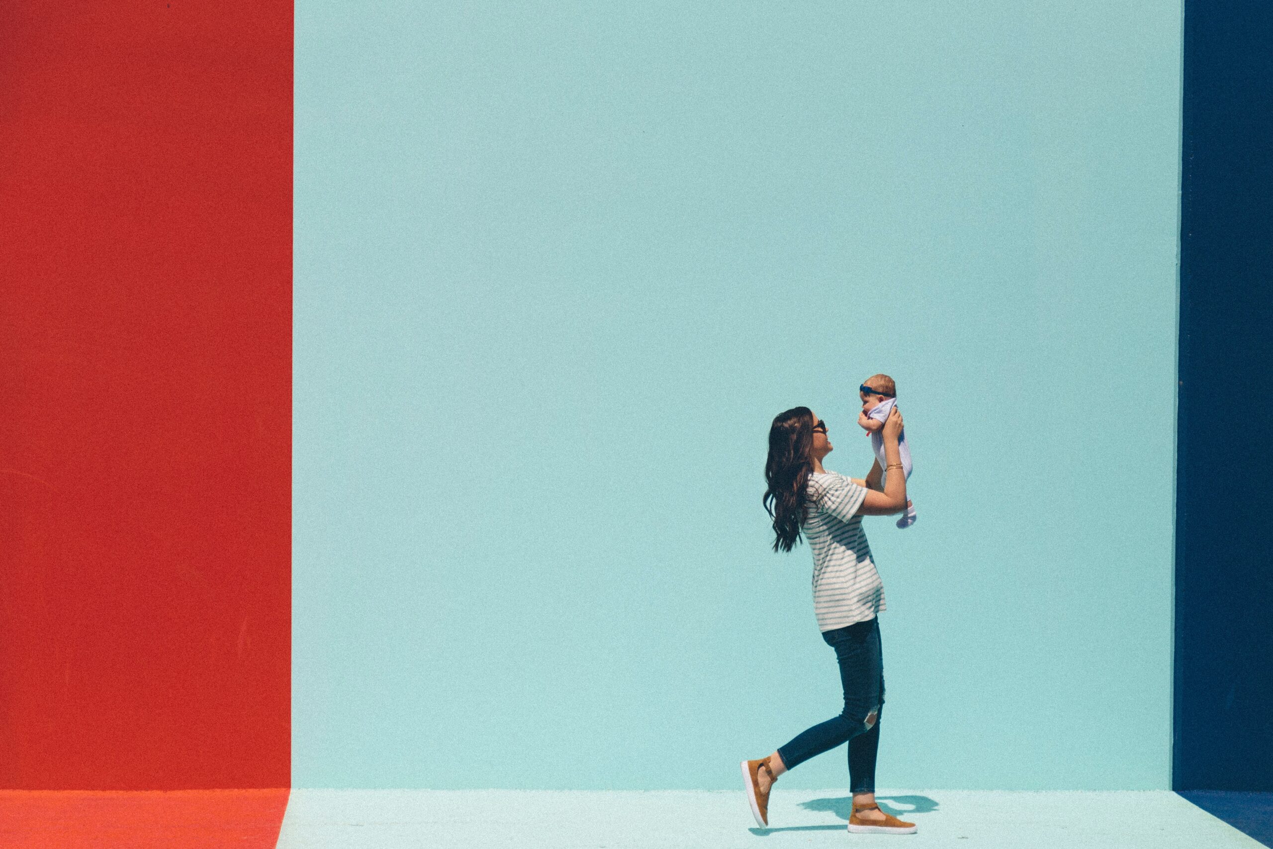 woman holding baby with bright turquoise background